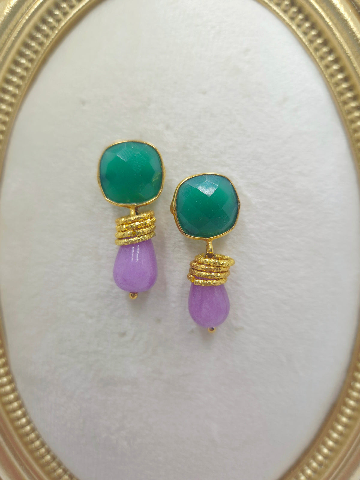 Close-up of green onyx studs and pale purple stone drops with gold-tone wraps